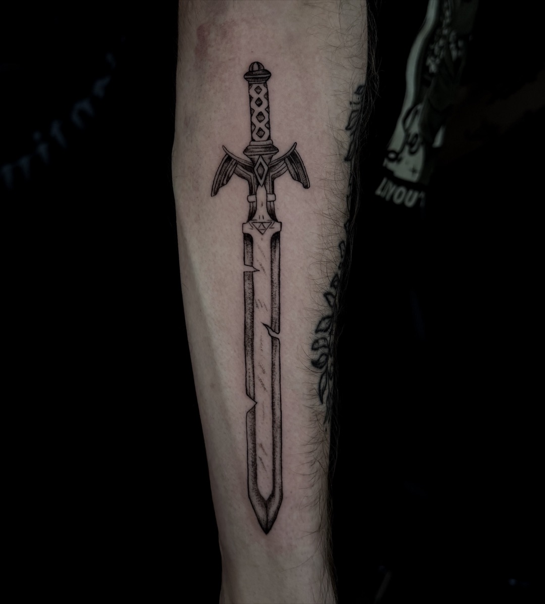 Zwart-grijze dotwork-tattoo van het Master Sword uit Zelda op een onderarm.