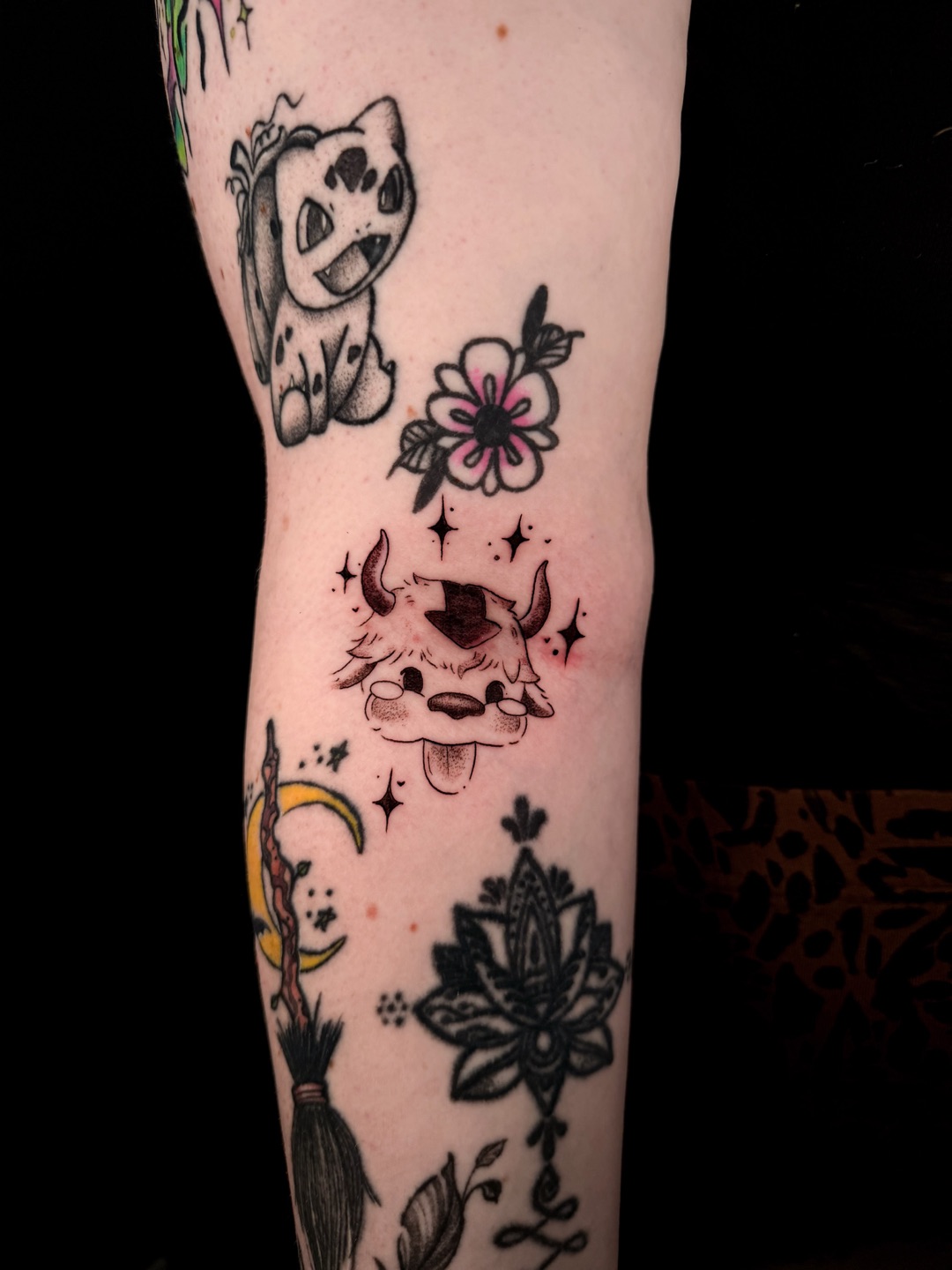 Twee schattige zwart-grijze tattoos op een arm: een dalmatiërpuppy en een harig hoorndiertje met sterretjes.